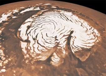 Вид  северной полярной шапки Марса, диаметр которой — около 1 000 км. Хорошо  видны Северный каньон (в правой нижней части ледового щита) и впадины.  (Иллюстрация НАСА / Caltech / JPL / E. DeJong / J. Craig / M. Stetson.)